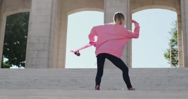 Femme danse sur les escaliers près de l'arche avec penny board dans les mains — Video