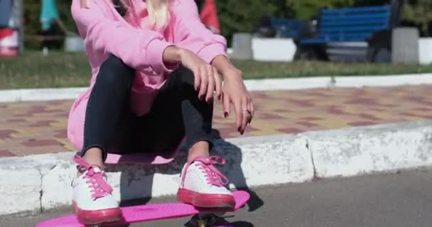Ung kvinna i hjälm leker med penny styrelse sitter på trottoaren — Stockvideo