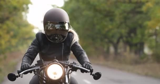 Mujer motociclista conduce a lo largo de la carretera entre árboles en otoño — Vídeos de Stock
