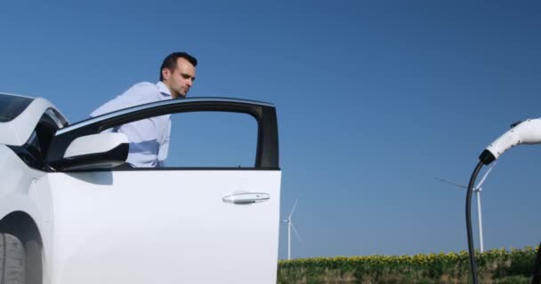 Ember csatlakozik dugó elektromos autó szélmalom állomás — Stock videók