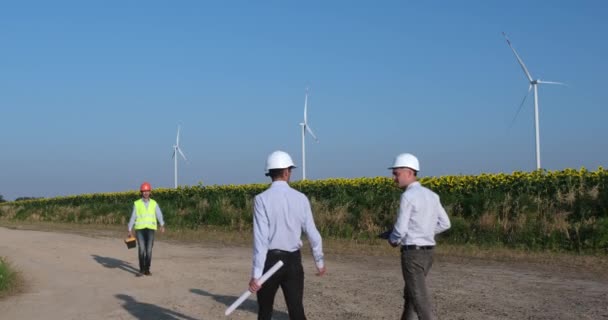 Especialistas em manutenção apertam as mãos contra moinhos de vento — Vídeo de Stock