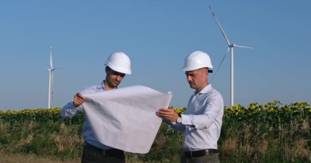 Инженеры обсуждают плакат холдинга против ветряных мельниц — стоковое видео