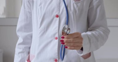 Doktor muayenehanedeki hastayı muayene etmeye hazırlanıyor, steteskopun bir parçasını elinde tutuyor ve onu çeviriyor..