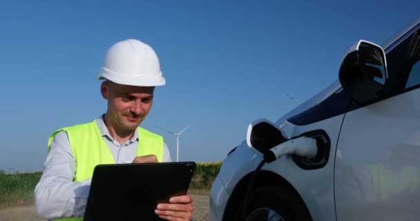 Ein Ingenieur Arbeitet Einem Laptop Neben Dem Ladestecker Für Elektroautos — Stockvideo