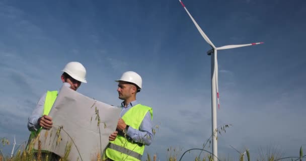 Muži diskutují o výstavbě větrného mlýna s kresbou a tabletem — Stock video