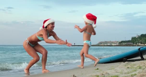 Mother and daughter play and hug near SUP board on sea beach — Wideo stockowe