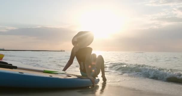 Mulher senta-se na praia arenosa e brinca com ondas marinhas espumosas — Vídeo de Stock