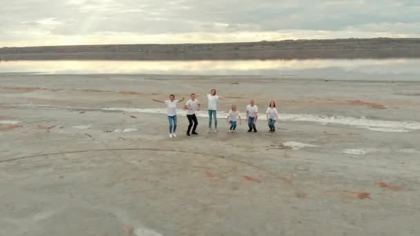 Team van vrienden springt en zwaait handen op vlakke rivieroever — Stockvideo