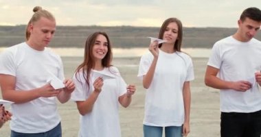 Erkek ve kız arkadaşlar nehir kıyısındaki uçaklarla el kaldırın.