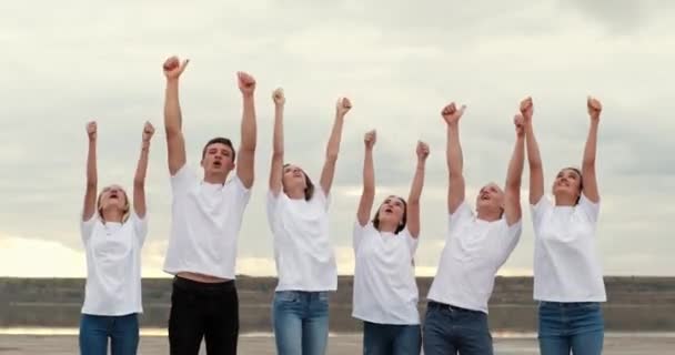 Team van tieners toont duimen omhoog kijkend op bewolkte hemel — Stockvideo
