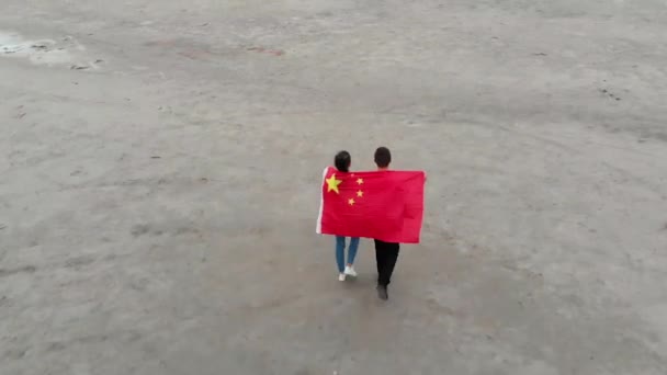 Genç çift el ele tutuşuyor ve Çin bayrağıyla kaplanmış şekilde yürüyor. — Stok video
