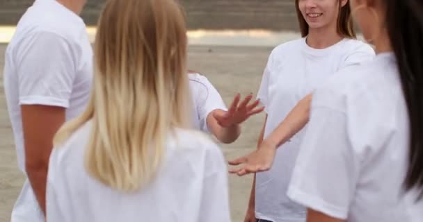 Друзі-підлітки схрещують руки, які яскраво посміхаються на березі річки — стокове відео