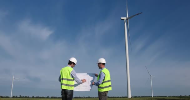 Men discuss windmills repairing with drawing and shake hands — Vídeo de Stock