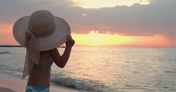 Meisje staat op het strand genietend van uitzicht op zee bij heldere zonsondergang — Stockvideo