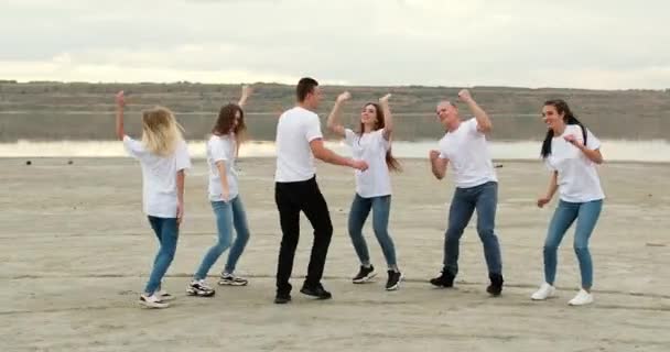 Team van vrienden danst en heeft plezier op rivier platte solide bank — Stockvideo