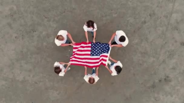 Team van vrienden ontvouwt Amerikaanse vlag staande in cirkel — Stockvideo