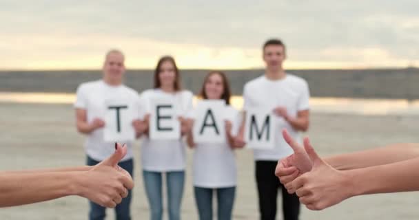 Друзі показують слово "Команда" як знак проти великих пальців на банку — стокове відео