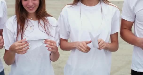 Друзі складають і показують паперові літаки з широкими посмішками — стокове відео
