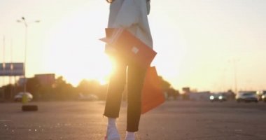 Genç bir kadın el sallıyor, bavullarıyla kaykaya basıyor.