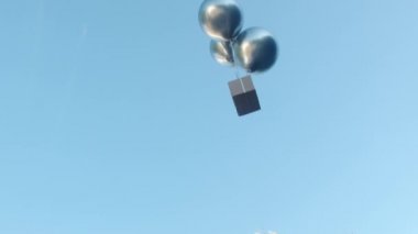 Gümüş helyum balonları gri kutuya bağlı uçar