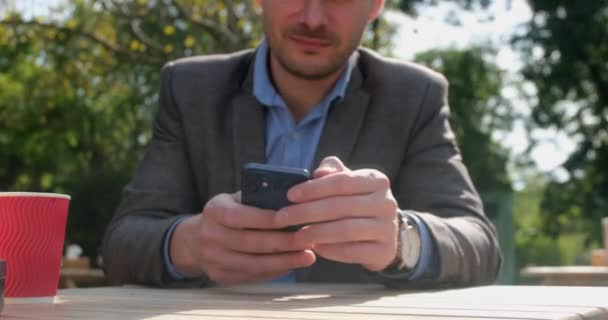 Podnikatel kontroluje sociální sítě sedí v pouliční kavárně — Stock video