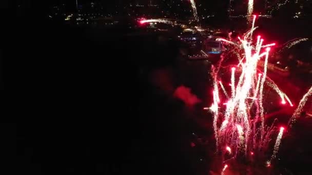 Donkere nacht stad met rood vuurwerk schijnt boven de rivier — Stockvideo