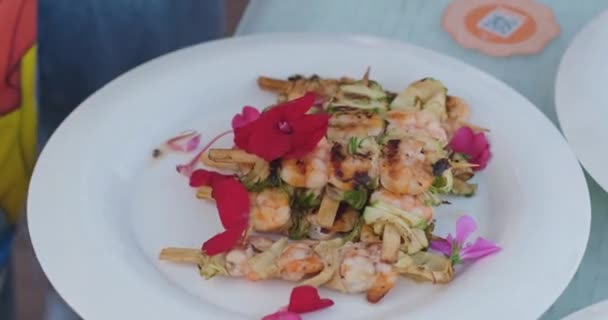 Grilled shrimps on sticks on plate decorated with flowers — Stock Video