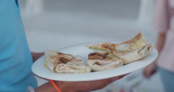 Gast zet pita wraps op plaat staan in de buurt van tafel op het feest — Stockvideo