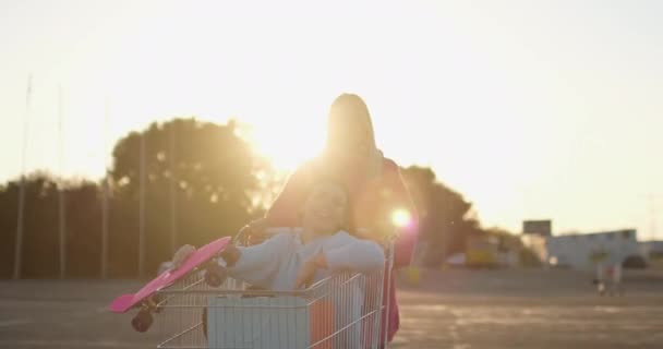Kız arkadaşlar alışveriş arabalarıyla otoparkta kayıyorlar. — Stok video