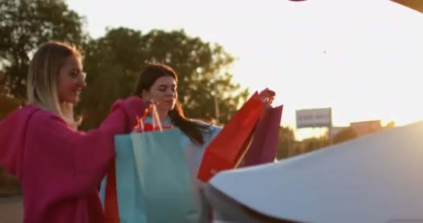Freundinnen treffen sich nach dem Einkaufen und verstecken Taschen im Kofferraum — Stockvideo
