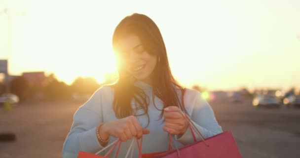 Jovem mostra sacos cheios de roupas e acessórios novos — Vídeo de Stock