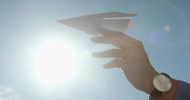 Homem mão segura avião de papel contra a luz solar brilhante de volta — Vídeo de Stock