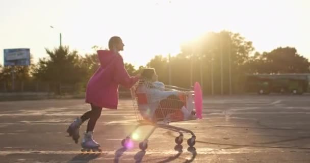 スケーター女性はショッピングトロリーで友人と楽しいスケートを持っています — ストック動画