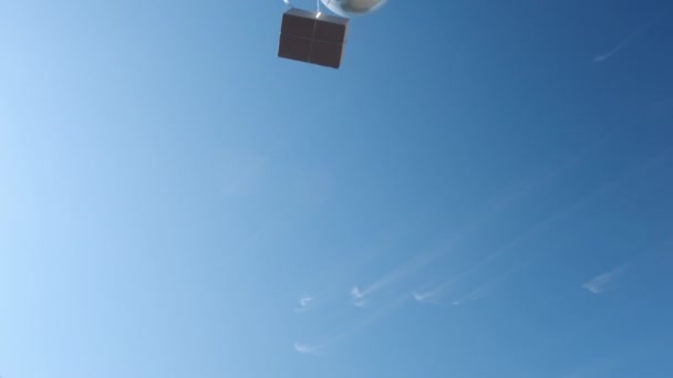 Caixa com grandes balões de prata voa para baixo contra o céu azul — Vídeo de Stock