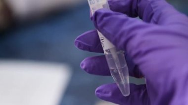 Bilim adamlarının elinde cam test tüpü var. Araştırma için örnek alıyorlar.