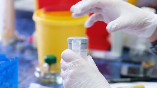 Cientista desaperta tampa de garrafa para derramar líquido do tubo de ensaio — Vídeo de Stock