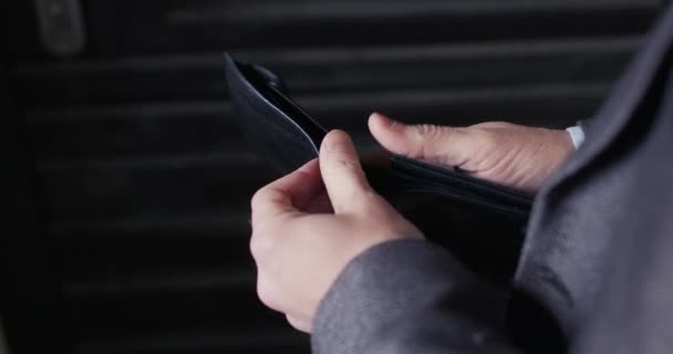 Man i jacka öppnar tom plånbok på mörk bakgrund — Stockvideo