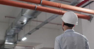 Miğferli mühendis otoparkta proje çizimlerini açıyor