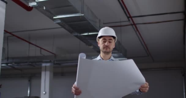 Engenheiro barbudo abre papéis de projeto no canteiro de obras — Vídeo de Stock