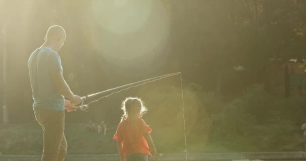 Apa Horgászbottal Horgászik Lánya Pedig Segít Lepkehálóval Naplementekor Kislány Boldog — Stock videók