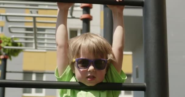 Boy Plays Alone Playground Small Child Sunglasses Shirt Has Fun — Stockvideo