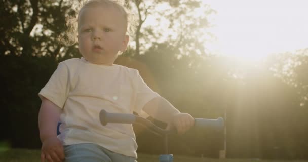 Χαριτωμένο Μικρό Αγόρι Ξανθά Μαλλιά Κάθεται Στο Ποδήλατο Στο Πίσω — Αρχείο Βίντεο