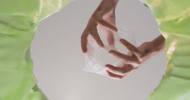 Person hands compress plastic tray and throw into green trash bin. Adult takes care of apartment throwing garbage in can close bottom view