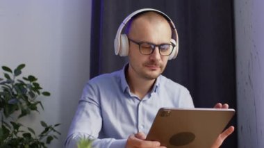 Man wearing white headphones waits team on video-calls for discussion about business. Happy chief starts business meeting about upgrading company