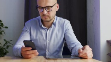 Businessman enjoys working on tablet looking for necessary information on Internet. Self-employed man checks phone for important messages