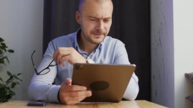 Self-employed worker looks with happy expression for results of new start-up on laptop. Man in glasses delighted with project looking in device