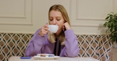 Sarışın bayan telefonu kontrol ettikten sonra hayal kırıklığına uğruyor. Bir kadın kafede oturuyor ve maçı kaybettiği için üzgün.