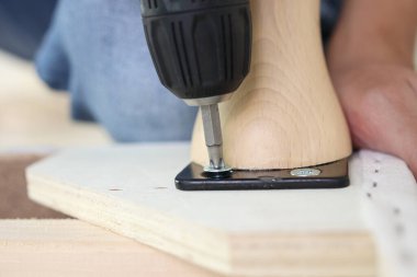 Adam evde kablosuz tornavida kullanarak mobilya monte ediyor.