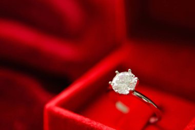 Kırmızı kumaş arka planda mücevher hediye kutusunda elmas yüzük.