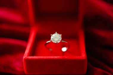 Kırmızı kumaş arka planda mücevher hediye kutusunda elmas yüzük.